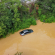 Aerial view of a car submerged under brown flood waters.
